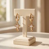 Caravanas de acero dorado con diseño de argolla y dije colgante en forma de cruz con incrustación de nácar.