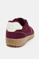 Zapatilla deportiva de gamuza color bordó con suela de goma y costuras en contraste blanco. Presenta detalle de talón en color blanco y cordones bicolores.