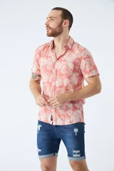 Camisa de manga corta con estampado botánico de hojas en tonos azul y blanco. Presenta cuello clásico, cierre frontal abotonado y corte slim.