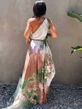 Vestido largo verde con diseño estampado tipo tie-dye y detalles dorados, de corte fluido, un solo hombro y diseño amplio.