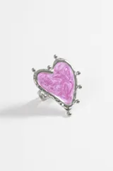 Anillo de acero quirúrgico plateado con diseño de corazón irregular y esmalte rosado efecto jaspeado en el centro, rodeado de pequeñas esferas metálicas decorativas.