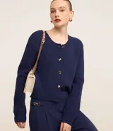 Cardigan azul marino de punto con cuello redondo, mangas largas y textura acanalada. Tiene abotonado delantero con botones mixtos.