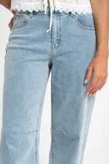 Jean de corte baggy con tiro medio, confeccionado en algodón peinado de tono celeste claro. Presenta un diseño de pierna amplia con costuras reforzadas en la zona de las rodillas.