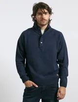 Sweater de punto color azul marino, con cuello alto, cierre frontal parcial y tapeta con botones. Presenta mangas raglán y puños y ruedo acanalados.