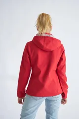 Campera de neopreno color rojo con capucha ajustable, cierre frontal completo y bolsillos laterales. Presenta puños ajustables con velcro y un parche circular decorativo en la manga izquierda.