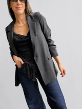 Blusa sin mangas de encaje negro con escote drapeado y bajo asimétrico adornado con flecos brillantes. Presenta breteles finos regulables y un diseño entallado.