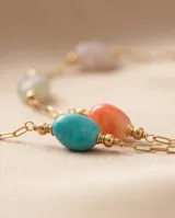 Collar de cadena fina con baño de oro, adornado con pequeñas piedras naturales de diversos colores distribuidas a lo largo de la pieza.