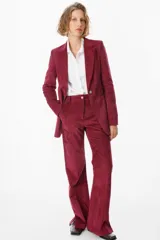 Blazer de corte clásico confeccionado en tela aterciopelada color bordó, con cuello solapa, cierre frontal con botones y bolsillos laterales tipo ojal.