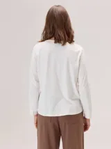 Remera de algodón con cuello redondo y manga larga. Presenta un diseño con costuras horizontales a la altura del pecho y costuras verticales en las mangas, brindando un detalle distintivo a la prenda.