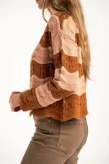 Sweater de tejido de punto con diseño de rayas horizontales onduladas en tonos marrón y beige. Presenta cuello redondo, mangas largas y corte oversize.