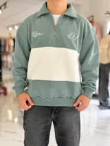 Buzo de algodón negro con una franja horizontal blanca en el centro, cuello solapa con medio cierre y puños y cintura elásticos acanalados. Cuenta con pequeños estampados en el pecho.