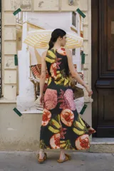 Vestido midi de popelina con cuello redondo, diseño sin mangas de corte semi-halter y lazos frontales para atar a la cintura. Estampado multicolor con motivos de mangos y flores.