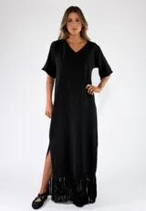 Vestido largo negro de punto con hilo brillante, escote en V, mangas cortas amplias, aberturas laterales y terminación con flecos en el ruedo.