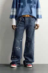 Jeans flare fit de denim azul oscuro con roturas y costuras decorativas en las perneras. Tiro medio y diseño de cinco bolsillos.
