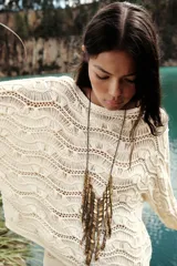 Sweater color crudo de punto calado con cuello barco y manga larga acampanada.