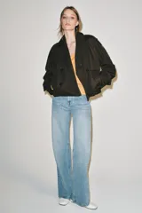 Trench corto Zara Woman Collection confeccionado en hilatura con algodón, en color verde militar. Presenta cuello solapa, manga larga con trabillas y botones en los puños, bolsillos delanteros, bajo asimétrico y cierre frontal cruzado con botones.