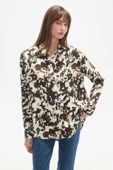 Camisa negra de viscosa con corte holgado, cuello clásico, cierre frontal de botones y detalle de tachas metálicas en la línea de los hombros.