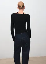 Camiseta de canalé color negro, de manga larga y diseño entallado con cuello halter y aberturas en los hombros.