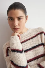 Sweater de tejido de punto grueso con diseño de rayas horizontales en tonos azul y rojo sobre base color natural, cuello redondo y mangas largas.