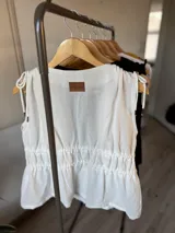 Musculosa blanca de tusor con breteles finos y escote en V con lazo ajustable.