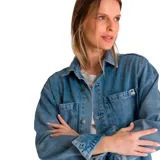 Camisa de denim celeste, corte oversize, con cuello clásico, cierre con botones a presión, mangas largas con puños abotonados, dos bolsillos con solapa abotonada en el pecho y aberturas laterales en el ruedo.