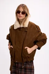 Campera de gamuza negra con cuello de piel sintética en color crema, cierre frontal, corte oversize y diseño estructurado con hombreras.