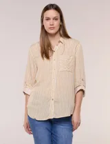 Camisa de corte clásico y silueta relajada con diseño de rayas verticales en blanco y negro. Presenta cuello camisero tradicional, cartera frontal con botones, un bolsillo aplicado en el pecho con rayas horizontales y mangas largas con sistema para arremangar.