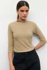 Polera de algodón color blanco, con cuello alto y mangas tres cuartos. Presenta un diseño ajustado al cuerpo con costuras decorativas en las sisas.