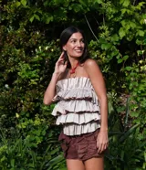 Top strapless con volados estructurados en capas en la parte delantera, creando volumen. El tejido es brocado en tonos beige y marrón claro con un patrón sutil.