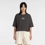 Remera New Balance de corte holgado y mangas cortas tipo raglán, color gris oscuro, con logo de la marca estampado en el centro del pecho.