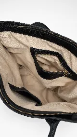 Cartera tipo tote bag de cuero vacuno color marrón oscuro, de diseño estructurado con asas largas para llevar al hombro y cierre superior. Presenta detalles de costuras decorativas y pespuntes en el frente.