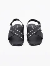 Sandalias negras de cuero sintético con tiras cruzadas y detalles de tachas plateadas.