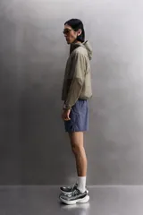 Chaqueta cortavientos de tejido técnico con estructura ripstop, cuello subido con capucha, cierre frontal de cremallera, bolsillos laterales ocultos y zonas perforadas para mayor transpirabilidad.