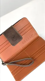 Billetera grande de cuero con solapa de cierre magnético, combinada con cuero vacuno con pelo en estampado animal print tricolor. Presenta un logo grabado de un búho en la solapa.