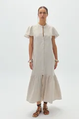 Vestido midi de lino color natural, con cuello mao, cierre frontal abotonado, mangas cortas con volados y falda con ruedo fruncido.