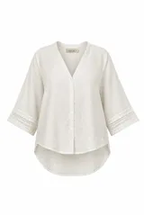 Camisa blanca de lino, con escote en V, mangas tres cuartos con detalles de encaje en los puños, cierre frontal de botones y diseño más largo en la parte trasera.