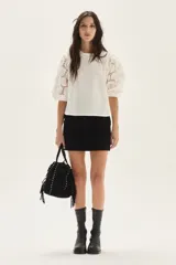 Blusa blanca de algodón con mangas abullonadas de broderie con diseño floreado. Presenta volados en el cuello y hombros, con un estilo romántico y femenino.