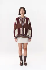 Cardigan de punto con diseño de bloques de color en tonos marrón, beige y verde. Presenta cuello redondo, cierre frontal con botones, mangas largas con hombros caídos y logo bordado en el frente.