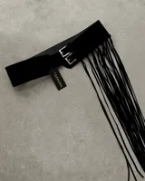 Cinto ancho de cuero sintético negro con doble hebilla plateada y flecos largos.