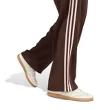 Pantalón deportivo Adidas modelo Firebird OS, color marrón con las clásicas tres tiras blancas a los lados y el logo del trifolio bordado. Cuenta con cintura elástica con cordón ajustable y diseño de corte recto y holgado.