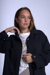 Sobrecamisa color beige confeccionada en gabardina, de corte holgado, con cuello camisero, cierre frontal con botones, dos bolsillos de parche en el pecho y mangas largas con puños abotonados.