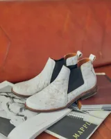 Botín Chelsea de cuero color beige con elástico lateral negro, puntera redondeada y suela plana.