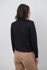 Polera de tejido de punto fino en color beige, con cuello alto y mangas largas con puños acanalados.