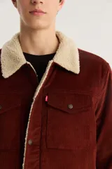 Campera marrón de pana con cuello y forro de sherpa color crema, cierre frontal con cremallera y bolsillos con solapa abotonada en el pecho.