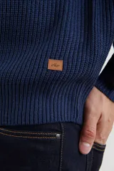 Sweater verde de punto inglés con cuello alto y cierre metálico frontal. Tiene mangas largas y terminaciones en punto canalé.