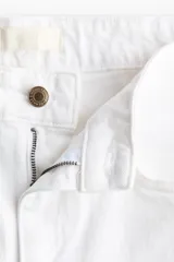 Jean de tiro alto con corte wide leg, confeccionado en denim de algodón con leve elasticidad. Presenta diseño clásico de cinco bolsillos, cierre frontal con botón y corte holgado desde el muslo hasta el bajo.