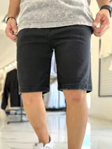 Bermuda de jean color negro, de corte clásico y largo por encima de las rodillas.