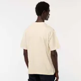 Camiseta de manga corta color crema, con cuello redondo y un bolsillo de parche en el lado izquierdo del pecho.