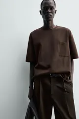 Remera de corte relajado confeccionada en tejido compacto de mezcla de algodón con elasticidad. Presenta cuello redondo, manga corta y un bolsillo frontal de plastrón.