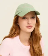 Gorra de sarga color verde con visera curva y bordado frontal con la frase "good days ahead" y detalles de flores en tono rosado.